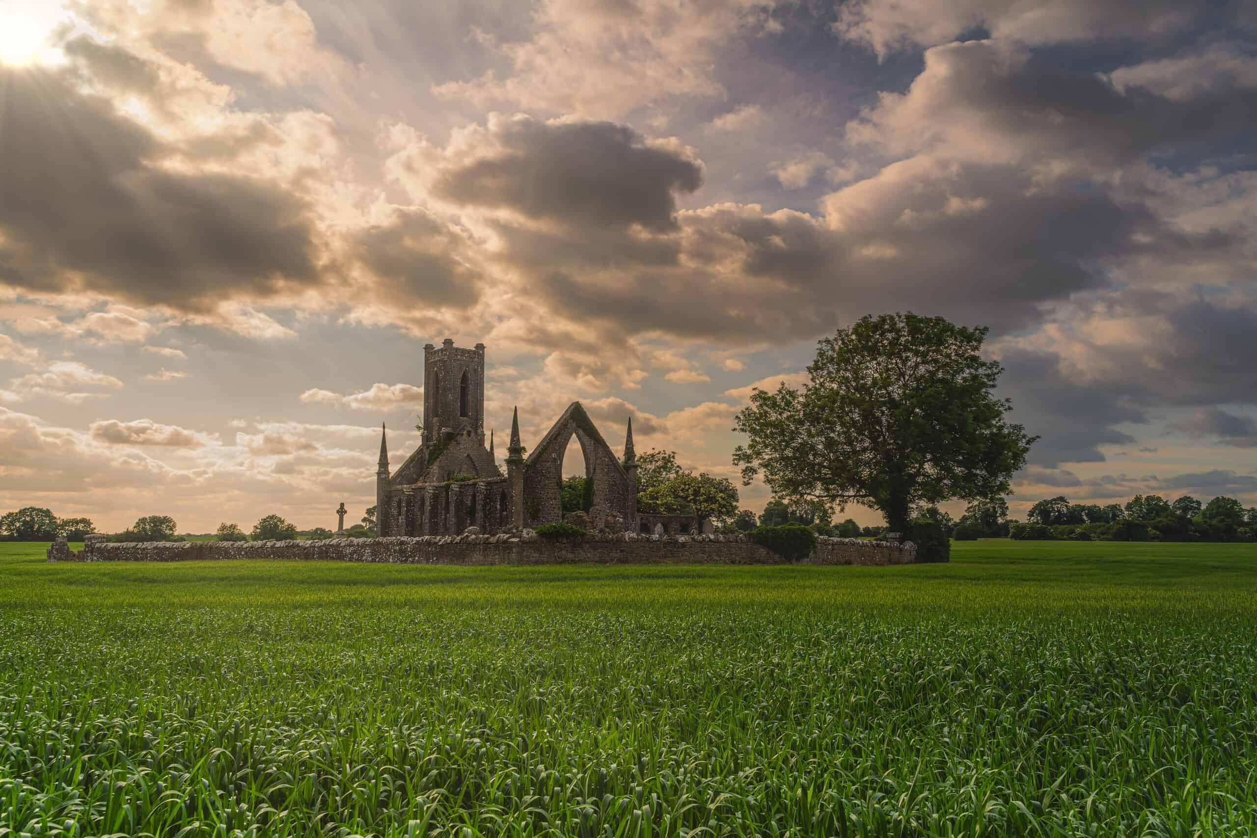 Old stone ruins and commentary of Ballinafagh Church with dramatic sky at sunset in background, County Kildare, Ireland